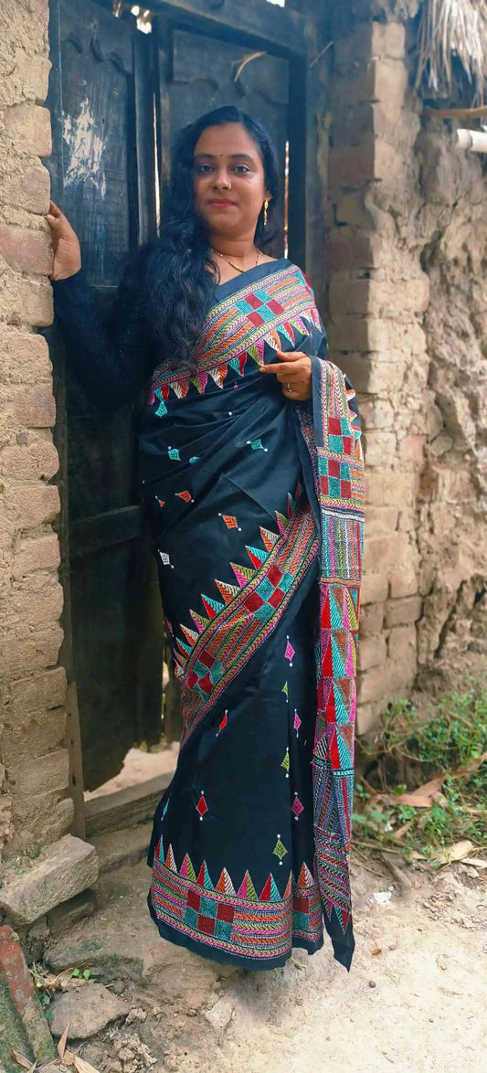 Close-up of red, teal and mustard geometric Kantha embroidery on black silk