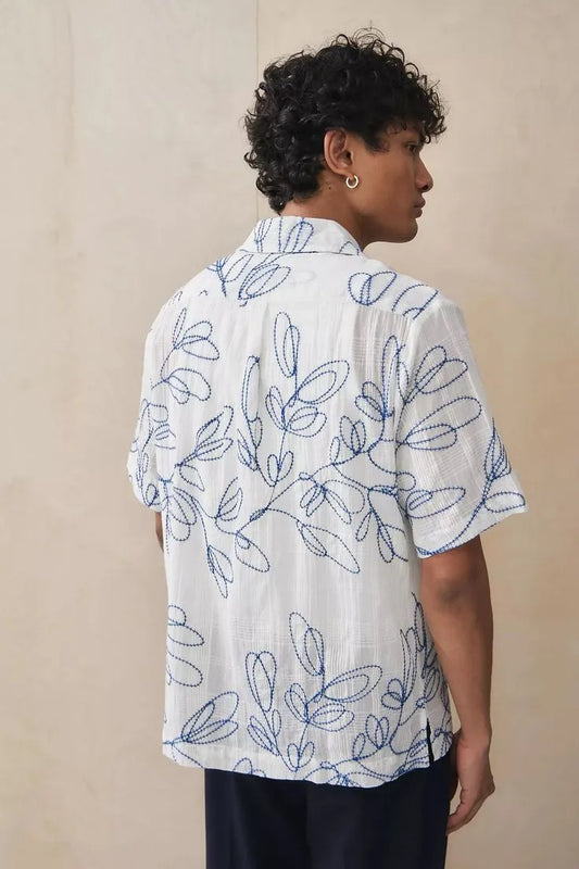 Close-up of blue leaf embroidery pattern on white cotton camp shirt